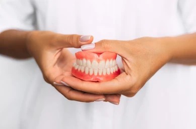 A close-up shot of a person holding a set of dentures
