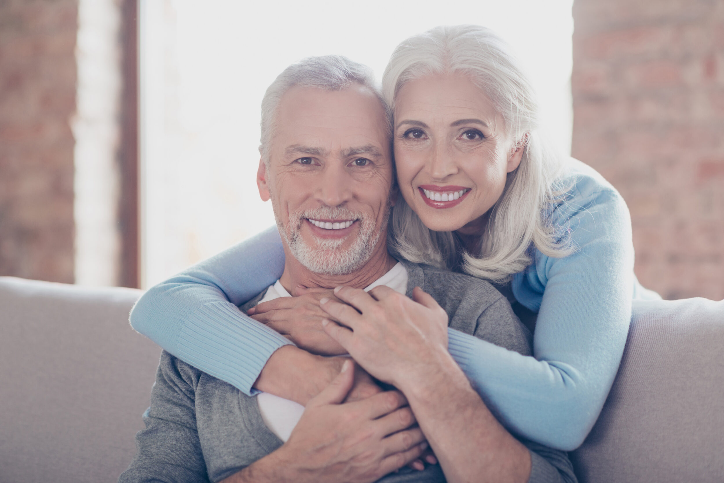 A man and woman smiling after getting hybrid dentures in Melbourne, FL