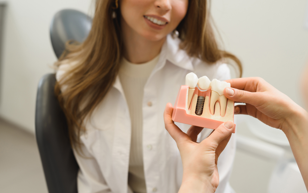 A dentist showing a woman a model of a dental implant A dentist showing a woman a model of a dental implant