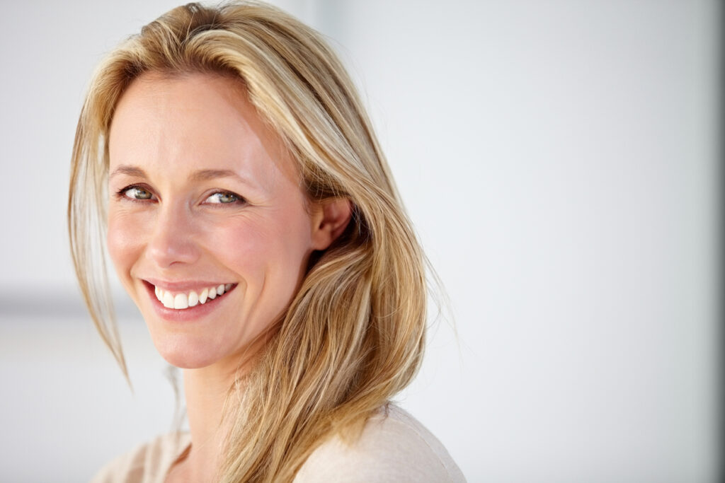 A woman smiling and showing the results of EmFace and a smile makeover in Melbourne, FL A woman smiling and showing the results of EmFace and a smile makeover in Melbourne, FL