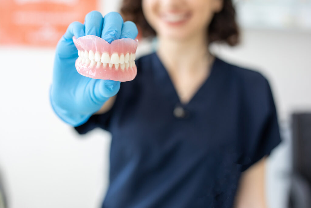 Dentist holding dentures for evaluation.